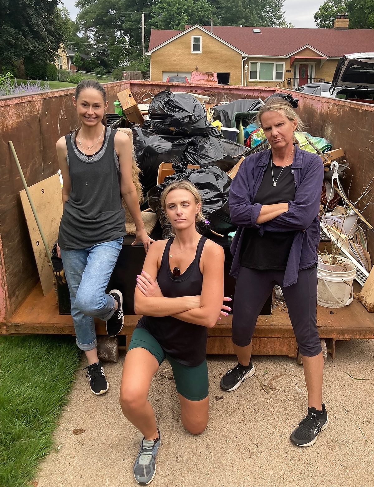 Three members of the Pro Packing crew in front of a loaded dumpster after a whole-house clearing